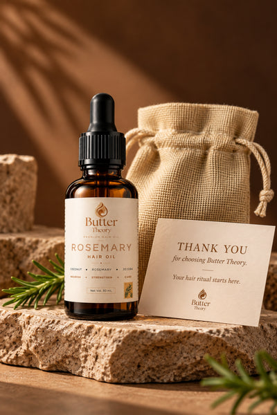 Butter Theory Rosemary Hair Oil in an amber glass dropper bottle, styled on a rustic stone slab with a burlap drawstring pouch and a thank you card in the background.